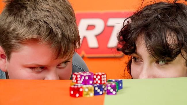 Zwei Buben schauen einander an, vor ihnen sind bunte Würfel aufgestapelt