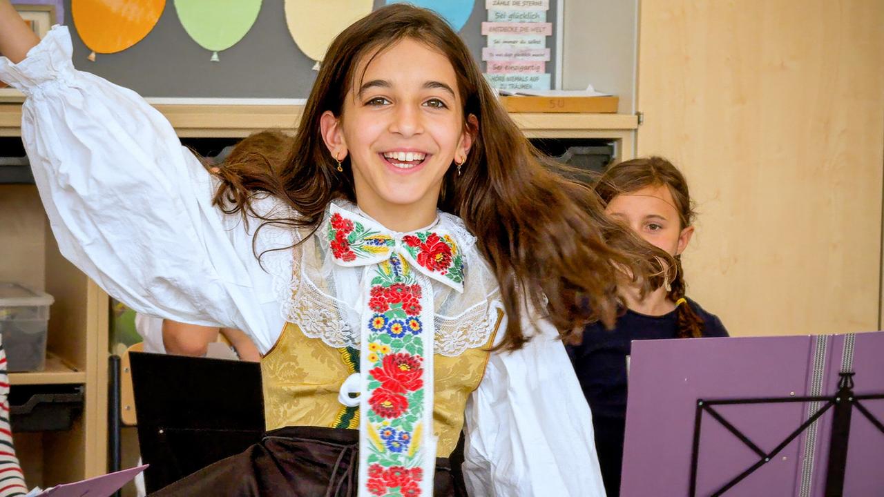 Ein Mädchen trägt eine Tracht und tanzt. 