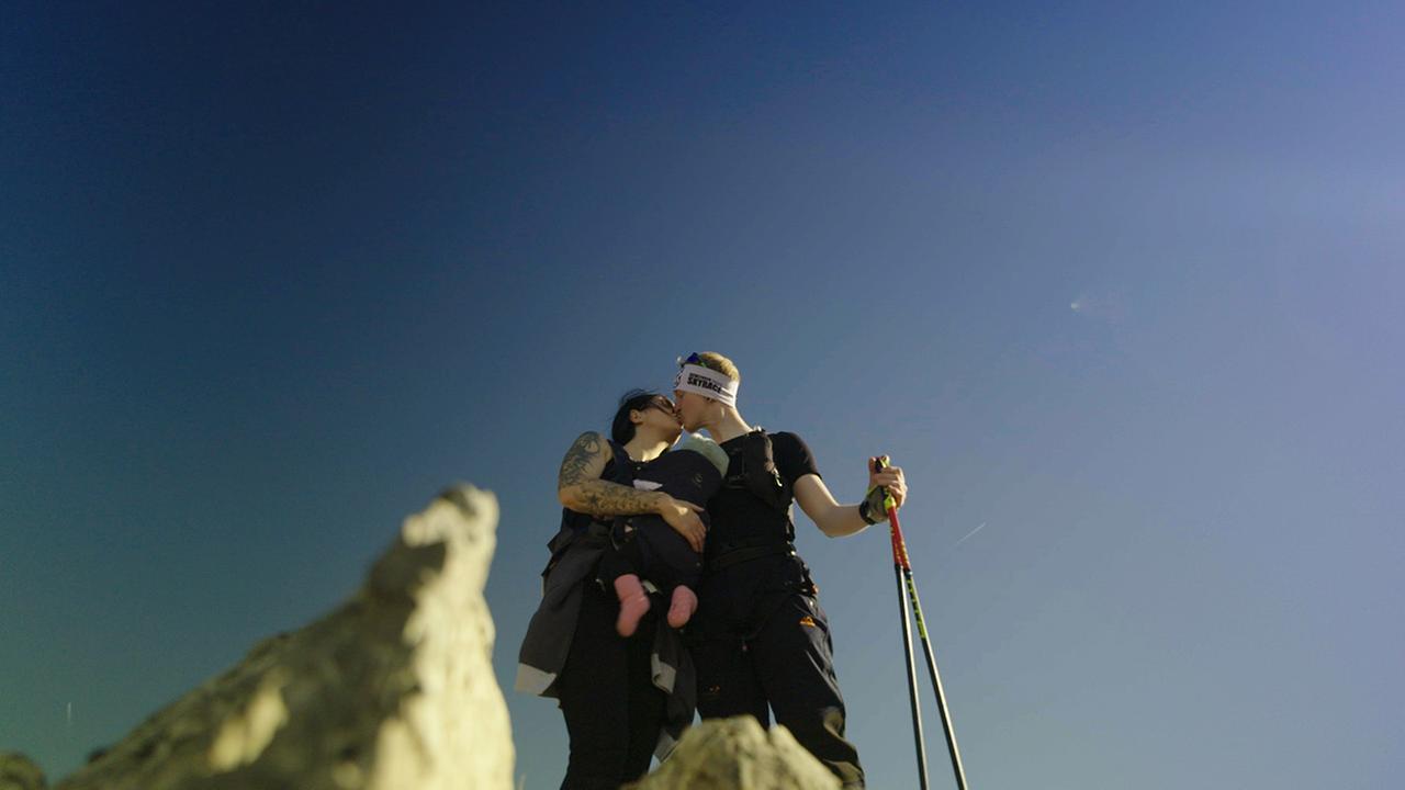Ein Paar mit Baby auf einem Berggipfel.