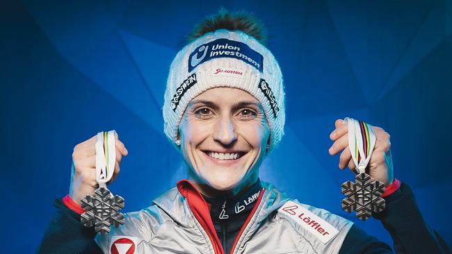 Die Skispringerin Eva Pinkelnig hält zwei Medaillen in die Kamera