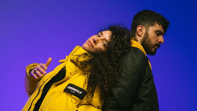 © Bild: Tim Cavadini Das Hip-Hop-Duo Esrap; die Geschrister Esra trägt eine gelbe Pufferjacke und lehnt RÜcken an Rücken an ihrem Bruder Enes, der schwarz gekleidet ist und seitlich zur Kamera steht