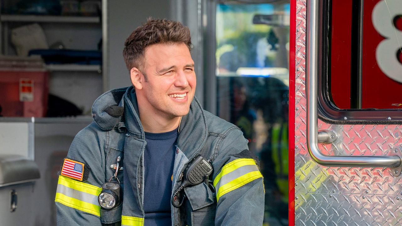 Ein Mann in Feuerwehrschutzkleidung sitzt entspannt in der Tür eines Einsatzfahrzeuges