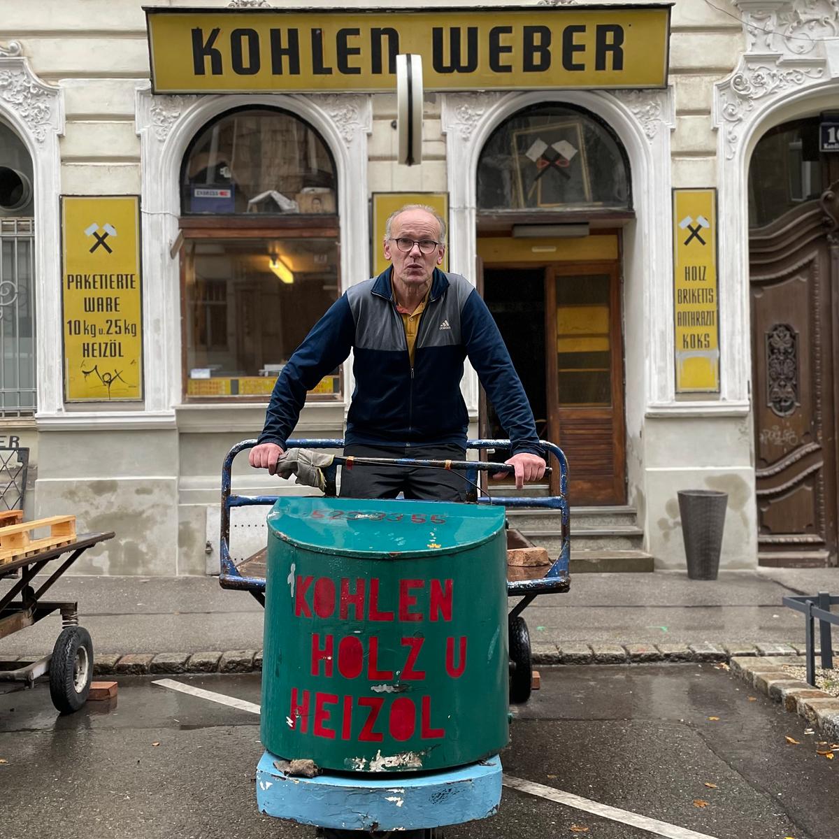Peter Hinterhoger ist einer der letzten Kohlenhändler in Wien. Er steht mit einem Lastenfahrzeug vor seinem Geschäft. Als Aufdruck ist zu lesen: Kohlen, Holz und Heizöl. Mittlerweile verkauft er mehr Holz als Kohle.