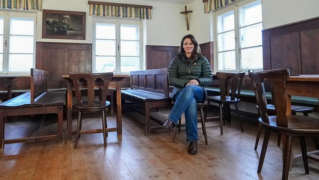 Lisa Gadenstätter sitze auf einem Sessel in der leeren Gaststube des ehemaligen „Gasthaus Zwink“ in Aspach. Hinter ihr sieht man ein Kreuz an der Wand hängend.