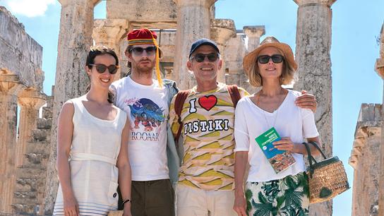 Ein Familienfoto auf der Akropolis, ein Mann mit seiner Frau, seine erwachsene Tochter und sein erwachsener Sohn, alle mit Sonnenbrillen blicken mehr oder weniger freundlich in die Kamera