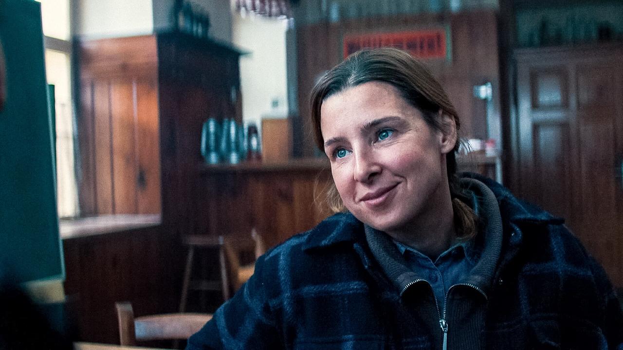 © ORF/Allegro Film Agnes sitzt lächelnd in einem holzgetäfelten Gasthaus.