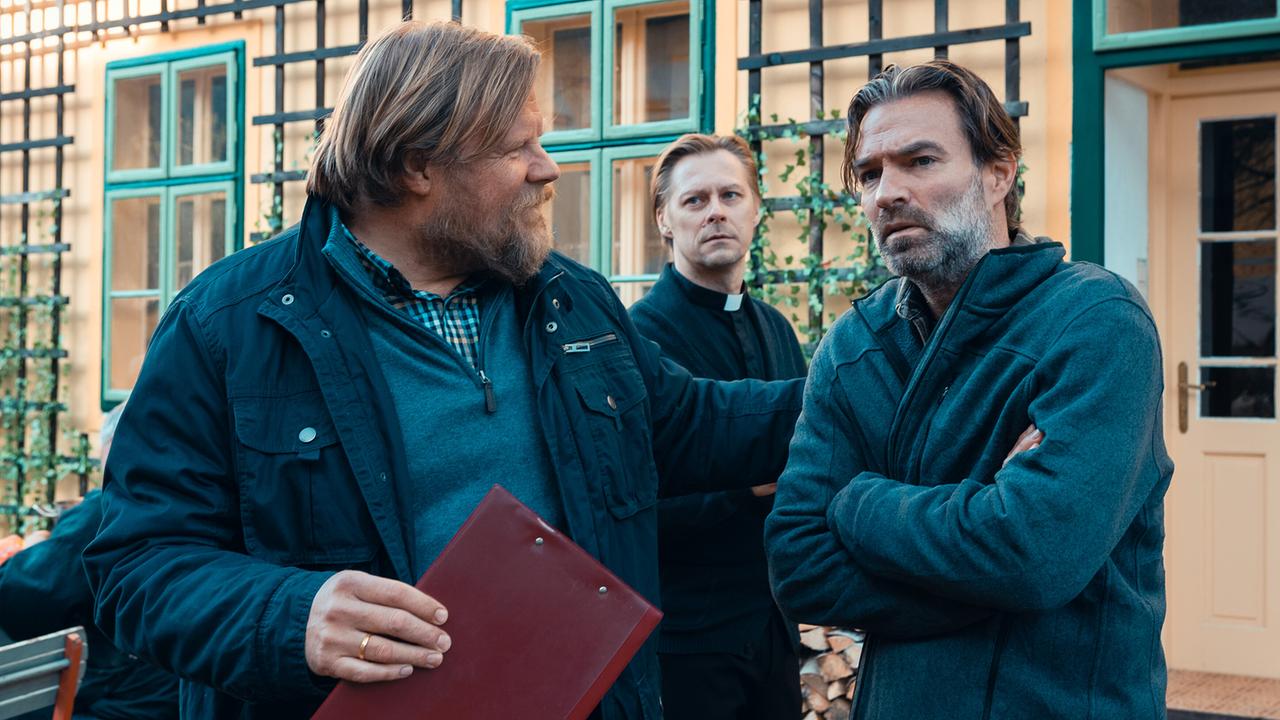 © ORF/Allegro Film/Anjeza Cikopano Bernhard mit verschränkten Armen steht mit Jens und Matias im Vorgarten eines Hauses.