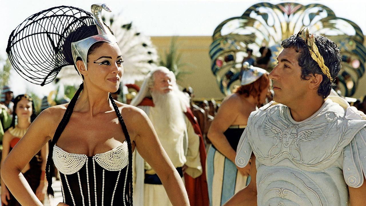 Im Bild: Siegessicher führt Cleopatra (Monica Bellucci) ihren Wettgegner Julius Cäsar (Alain Chabat) zur Baustelle.
