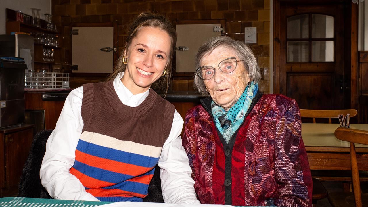 © ORF/Jenseide OG/Robert Oberzaucher Kira Schinko mit der 92-jährigen Wirtin „Mizi“ Ganglmair sitzen nebeneinander an einem Tisch in der Wirtshausstube.