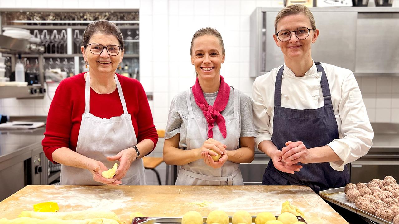 © ORF/Jenseide OG Kira Saskia Schinko, Theresia Palmetzhofer und ihre Mutter stehen in der Küche im Gasthaus "Zur Palme" hinter einer Arbeitsfläche und formen Teig zu gleichmäßigen Knödeln.