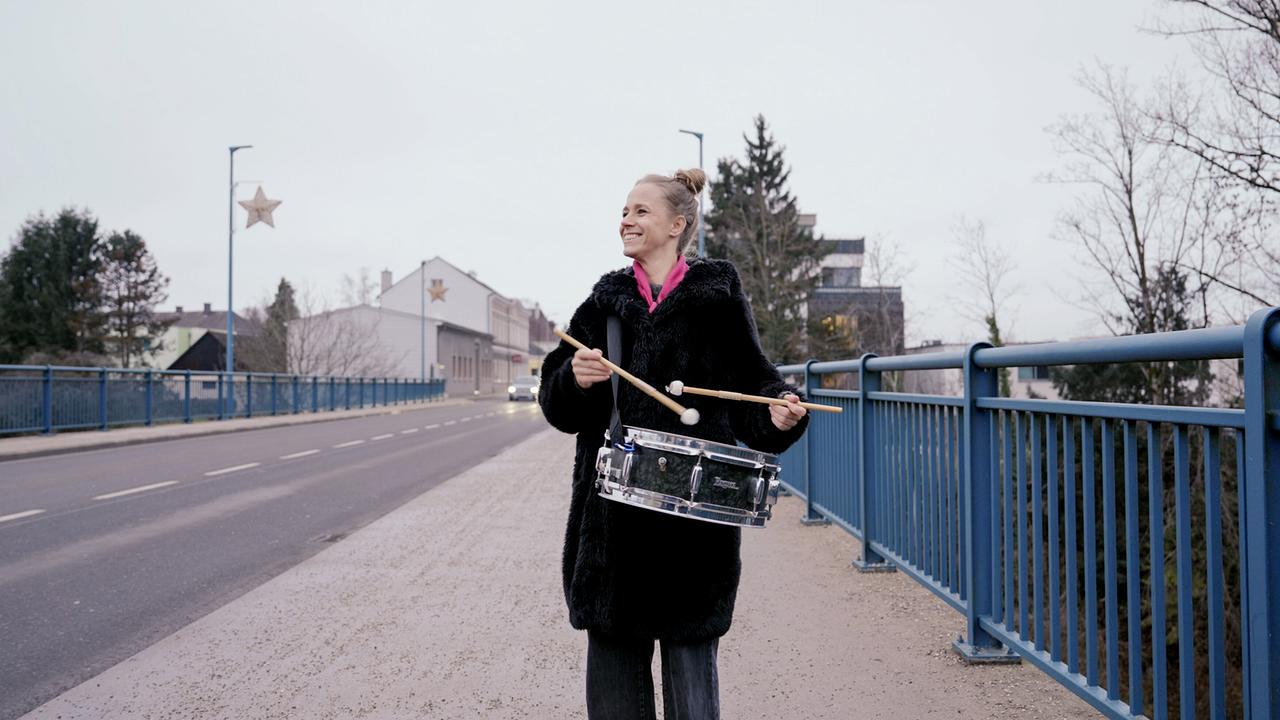 Kira Schinko steht mit einer Trommel auf einer Brücke in Hausmenning, Neuhofen in Niederösterreich