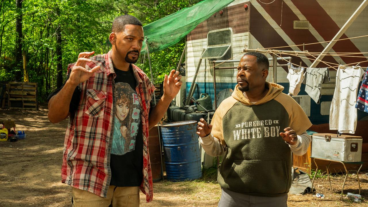 © ORF/Sony Pictures/CTMG/Frank Masi Will Smith als Mike Lowrey und Martin Lawrence als Marcus Burnett in Freizeitkleidung vor einem heruntergekommenen Trailer, auf der Wäscheleine hängen Kleidungsstücke, beide halten die Hände hoch