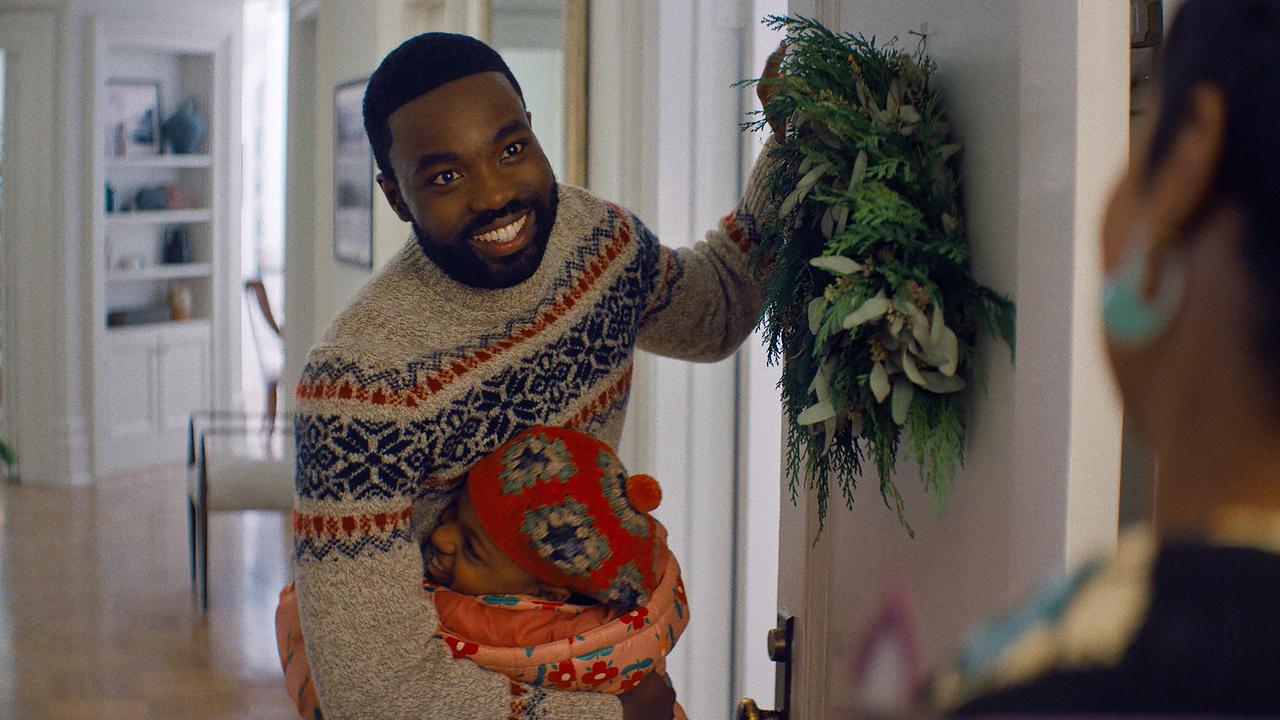 © ORF/Universal Pictures/Peacock Ein Mann in Winterpullover öffnet eine weihnachtlich geschmückte Haustür und begrüßt ein Kind und eine Frau herzlich