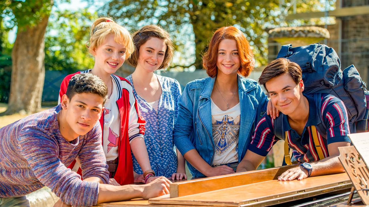© ORF/DCM Film/Andreas Schlieter Bibi Blockberg und Tina Martin stehen mit Adea, Tarik und Alex im Freien an einem Klavier und lächeln freundlich in die Kamera