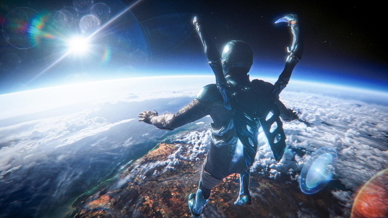 © ORF/Warner Bros. Pictures Xolo Maridueña als Superheld Blue Beetle, in seiner Rüstung fliegt er im Orbit und blickt auf die Erde und die hinter ihr aufgehende Sonne