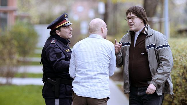 Robert Palfrader in Polizeiuniform steht mit Nicholas Ofczarek in Freizeitkleidung und einem weiteren Mann im Freien einer Wohnanlage