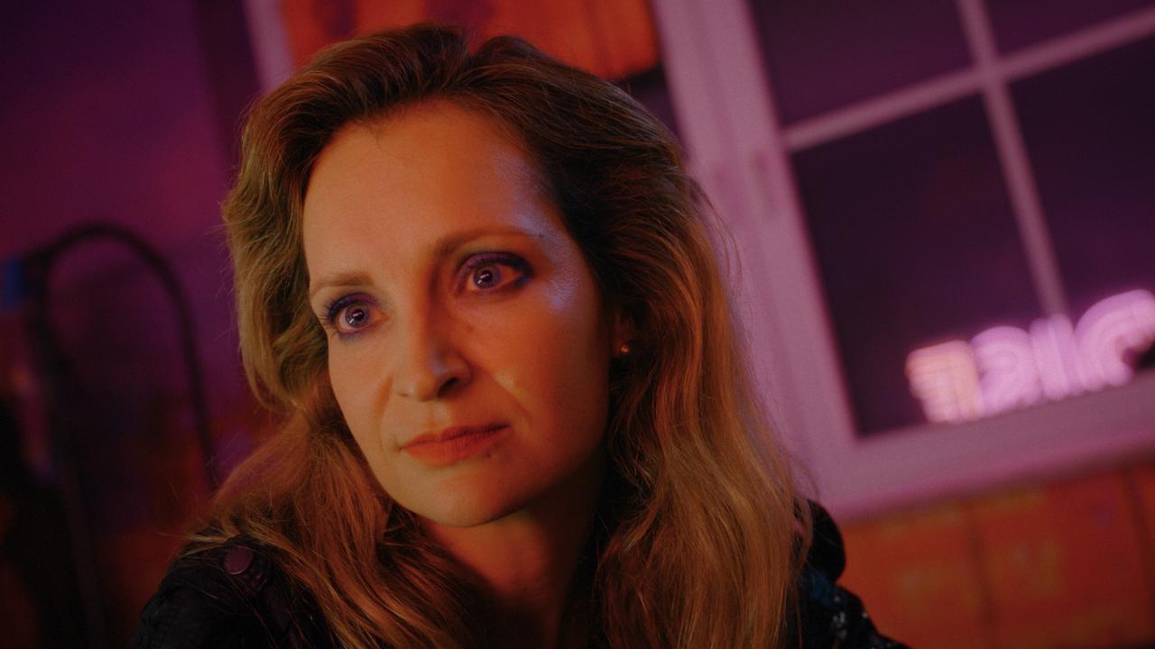 © ORF/Superfilm Nahaufnahme von Babs Tschach in einem Raum mit warmem, farbigem Licht und nächtlicher Atmosphäre.