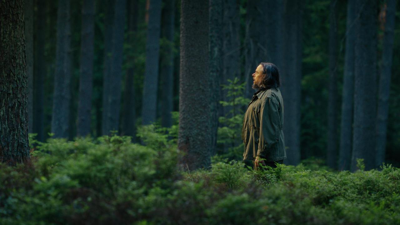 © ORF/Superfilm Reinhard Matussek steht in einem dichten Wald zwischen hohen, gleichmäßig gewachsenen Bäumen und Büschen.