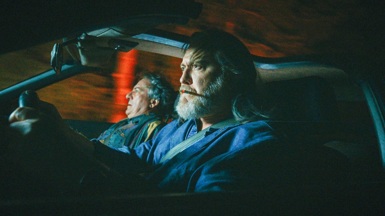 Richard Pfeisinger am Lenkrad und Gerri Tschach daneben fahren nachts in einem Auto.