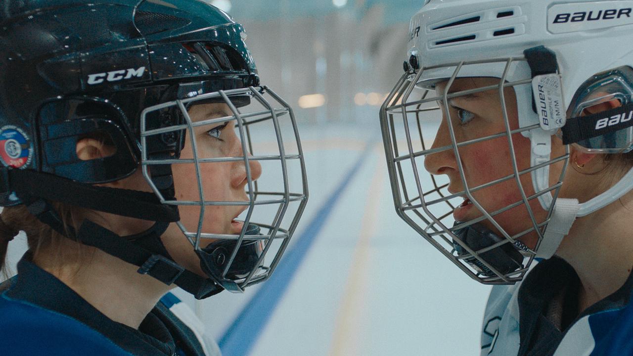 Die zwei Eishockeyspielerinnen Mira und Theresa stehen sich in voller Ausrüstung auf dem Eis gegenüber und blicken sich wütend an.