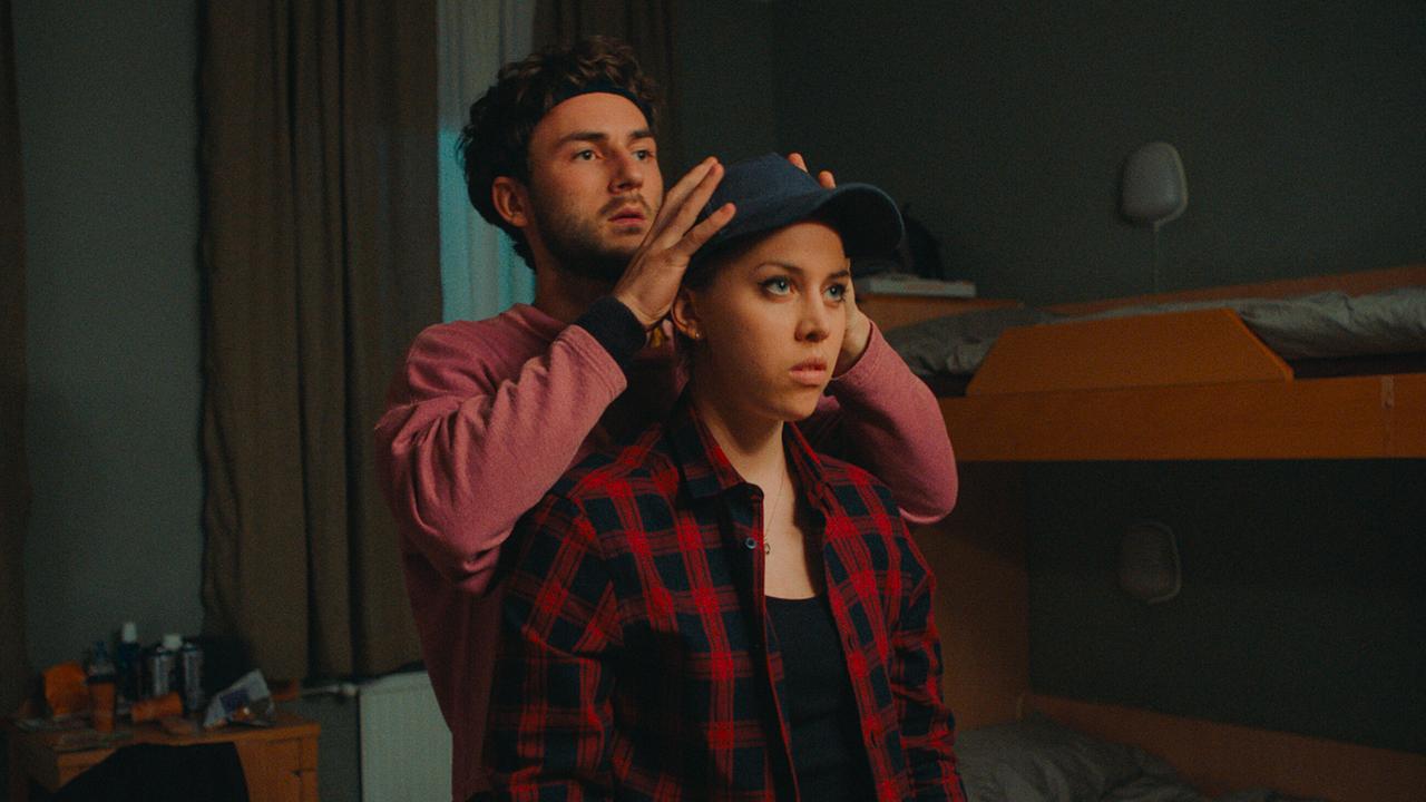 Paul setzt Mira eine Kappe auf in einem Zimmer mit einem Stockbett.