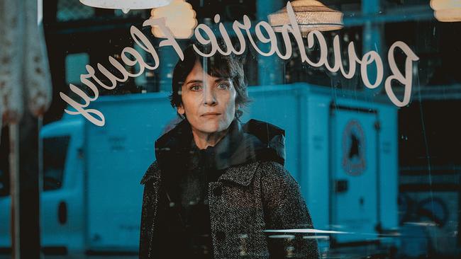 Charly Fleury steht am Abend vor einer Fleischhauerei und blickt durch die Scheibe durch das beleuchtete Geschäft, spiegelverkehrt ist in Schreibschrift Boucherie Fleury zu lesen