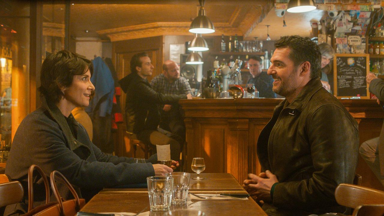 © ORF/Vuelta Entertainment/Les Films du Cap/MM Films/Orange Studio Charly Fleury und Martial Toussaint sitzten an einem Tisch eines Wirtshauses und unterhalten sich freundlich miteinander
