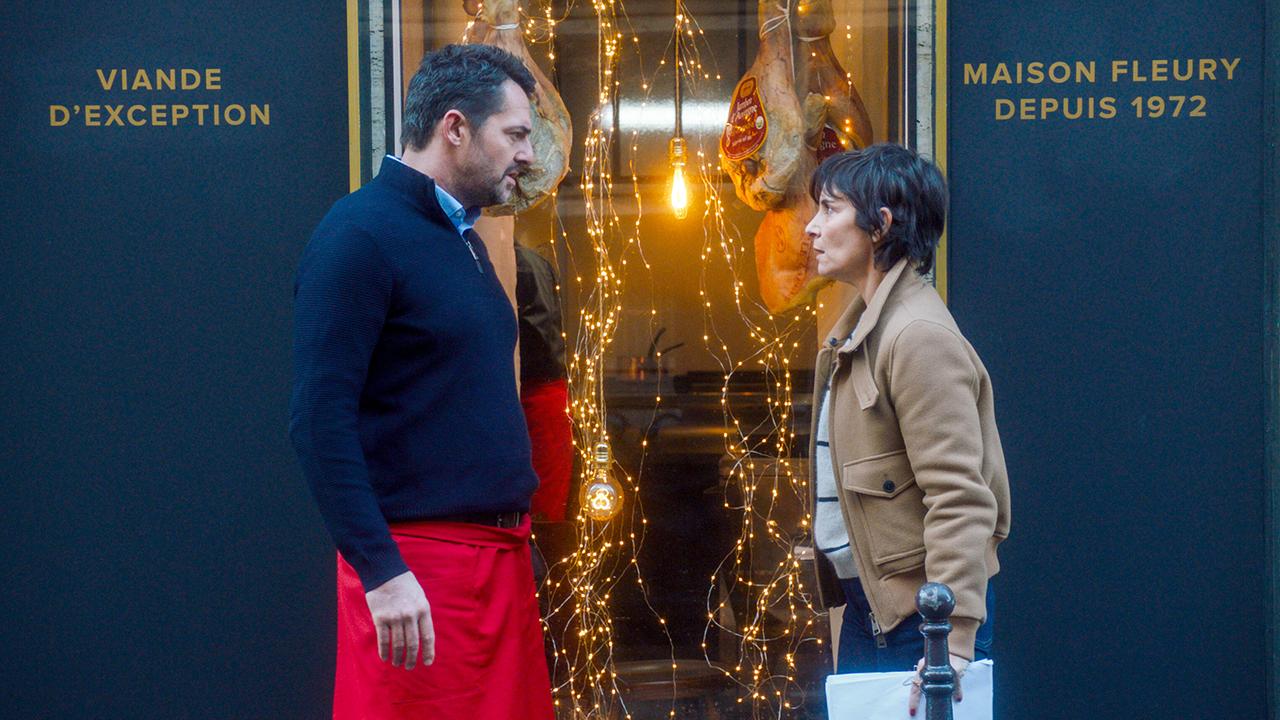 Martial Toussaint und Charly Fleury stehen einander vor dem festlich beleuchteten Schaufenster einer Metzgerei gegenüber.