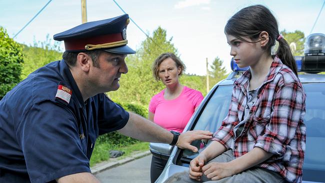 © ORF/Petro Domenigg Martin Leutgeb in Polizeiuniform spricht mit Melanie Hauser, die auf der Motorhaube eines Polizeiautos sitzt. Birgit Mayr  beobachtet im Hintergrund das Gespräch.