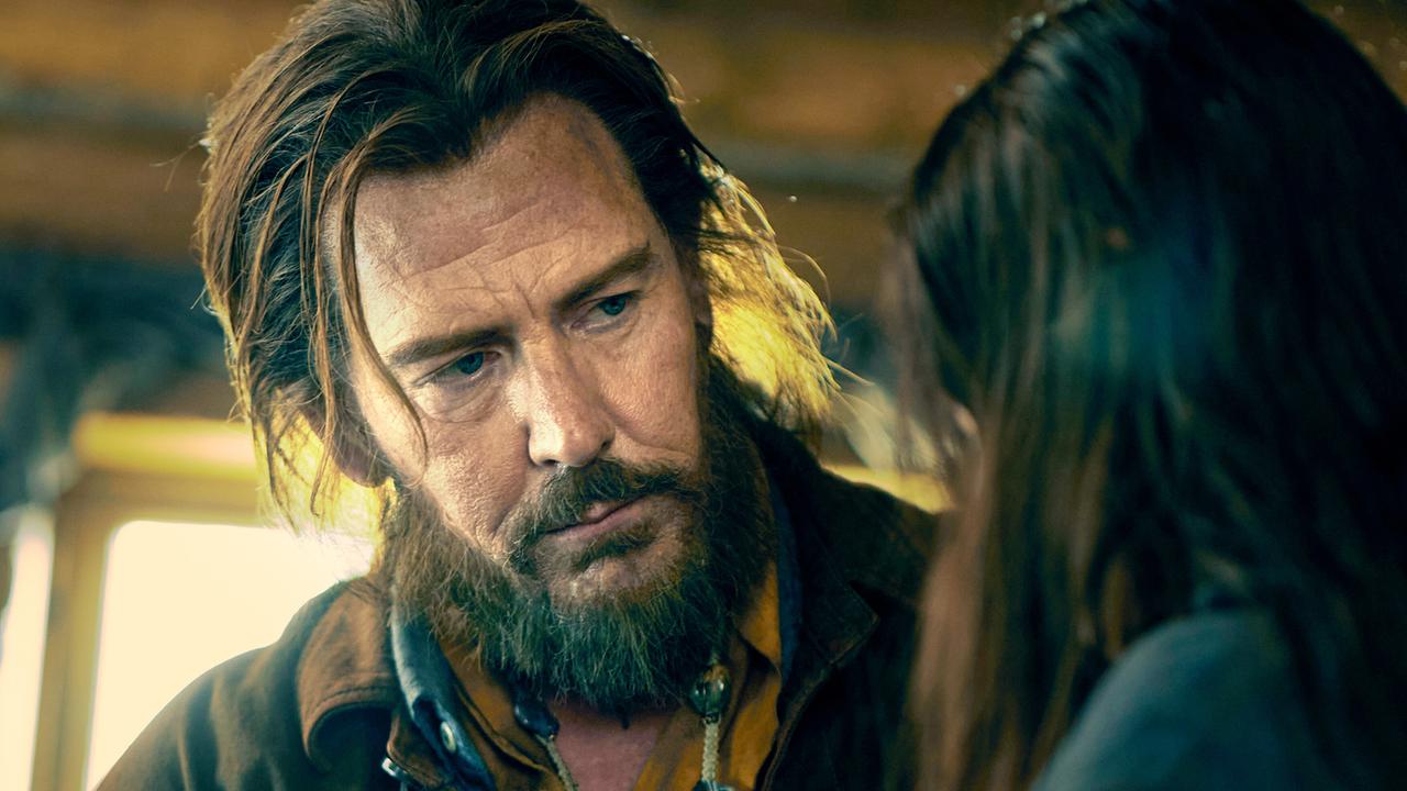 Ein Mann mit Bart und langen Haaren blickt auf eine schwarzhaarige Frau, die nur von hinten zu sehen ist