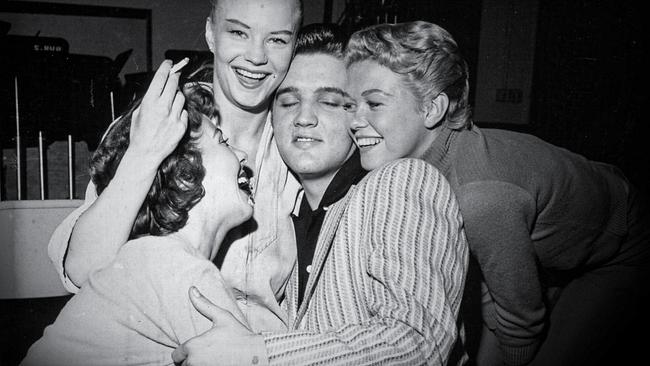 Schwarz-Weiß-Bild von Elvis Presley, eng umschlungen mit drei Frauen