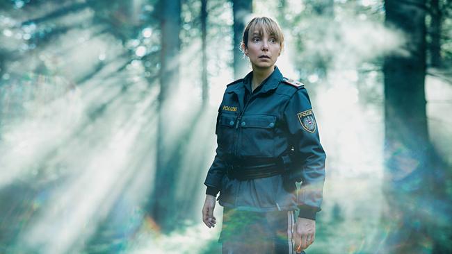  Polizistin Pia Krauss steht im diffusen Licht eines nebligen Waldes.