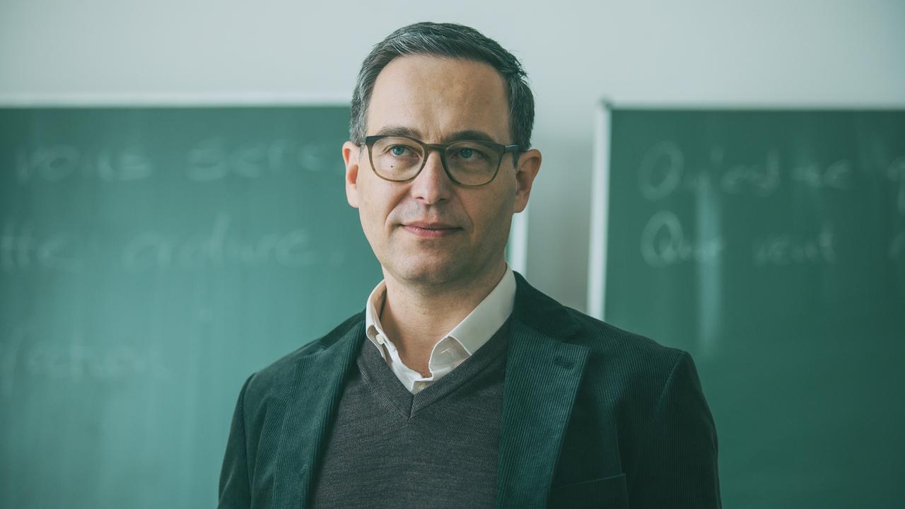 © ORF/ARD Degeto/Mona Film/Victoria Herbig Lehrer Markus Bichler steht im Klassenzimmer und hört den Ausführungen seiner Schülerin Vivian zu.