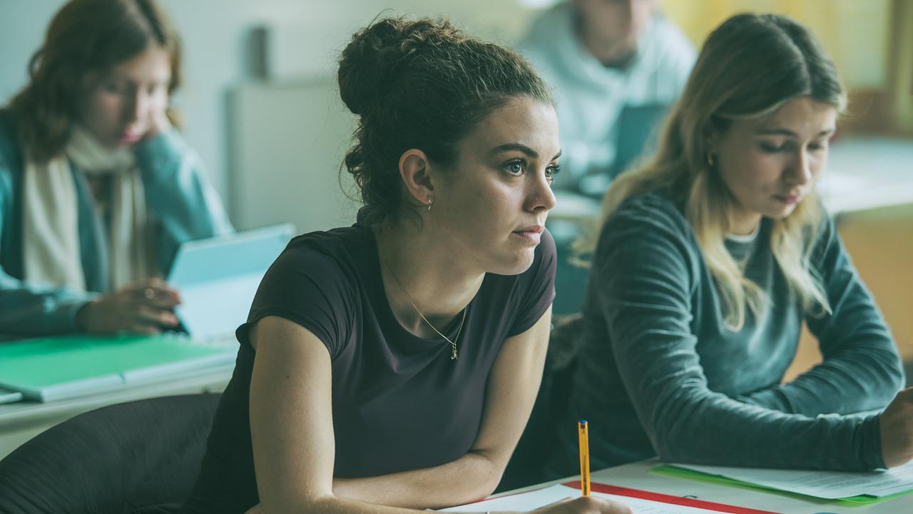 © ORF/ARD Degeto/Mona Film/Victoria Herbig Vivian sitzt im Klassenzimmer und hört den Fragen ihres Lehrers Herrn Bichler zu.