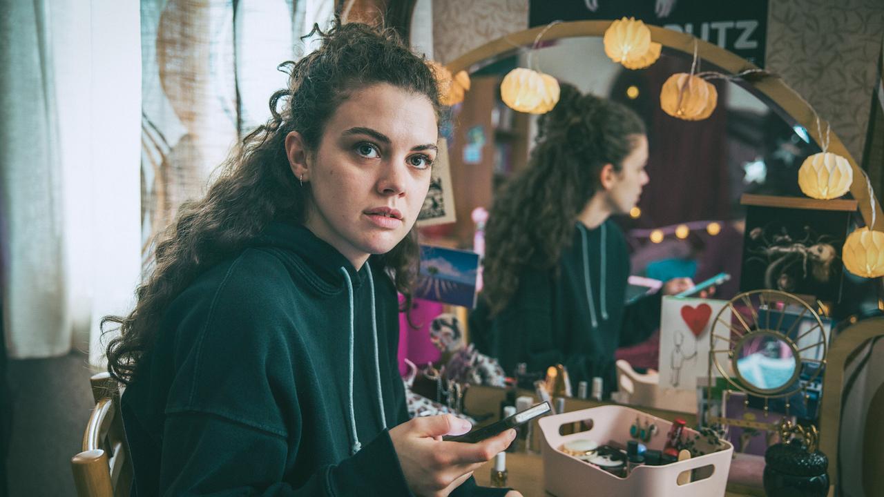 Vivian sitzt an Amelies Schminktisch und erzählt ihrer Mutter von Textnachrichten, die sie von Amelie erhalten hat.