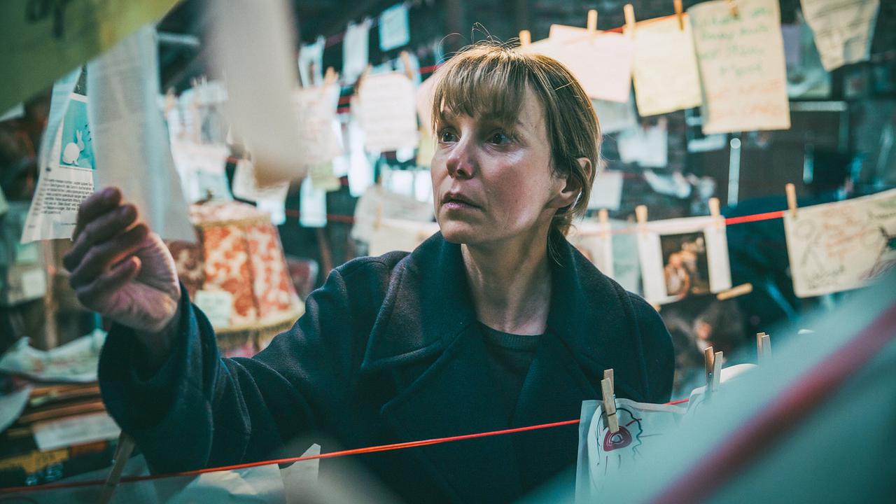 Pia sieht sich einen Zettel ihrer Beweissammlung in der Scheune an.