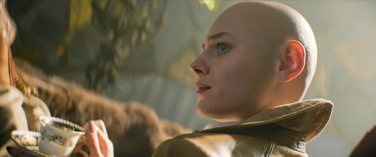 © ORF/Disney/20th Century Studios/Marvel Emma Corrin als kahlköpfige Cassandra Nova, in einem cremefarbenen Ledermantel mit großem Kragen blickt sie aufmerksam zur Seite