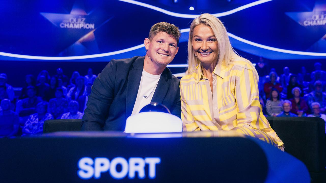 © ORF/ZDF/Thomas Kierok Thomas Morgenstern und Franziska van Almsick lächeln am Pult der Kategorie „Sport“ in die Kamera bei "Der Quiz Champion".