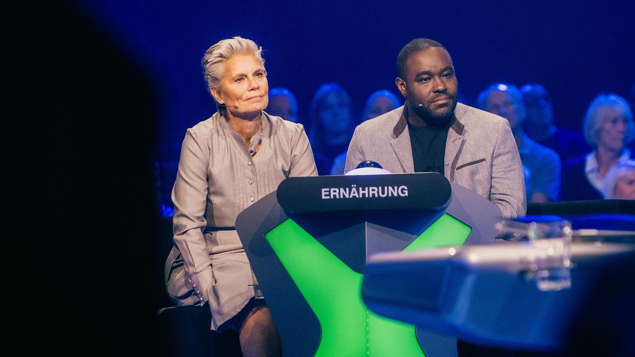 © ORF/ZDF/Thomas Kierok Sarah Wiener und Nelson Müller sitzen konzentriert am Pult der Kategorie „Ernährung“ bei "Der Quiz Champion".