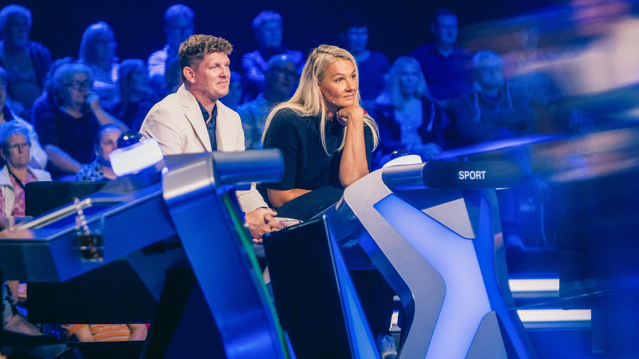 © ORF/ZDF/Thomas Kierok Thomas Morgenstern und Franziska van Almsick sitzen am blau beleuchteten Ratetisch der Kategorie „Sport“ vor dem Studiopublikum bei "Der Quiz Champion".