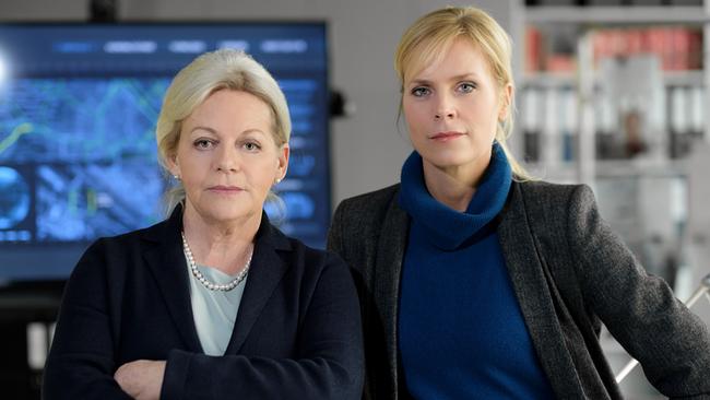 Henriette Wolf und Ina Zimmermann stehen in einem modernen Büro vor einem großen Monitor.