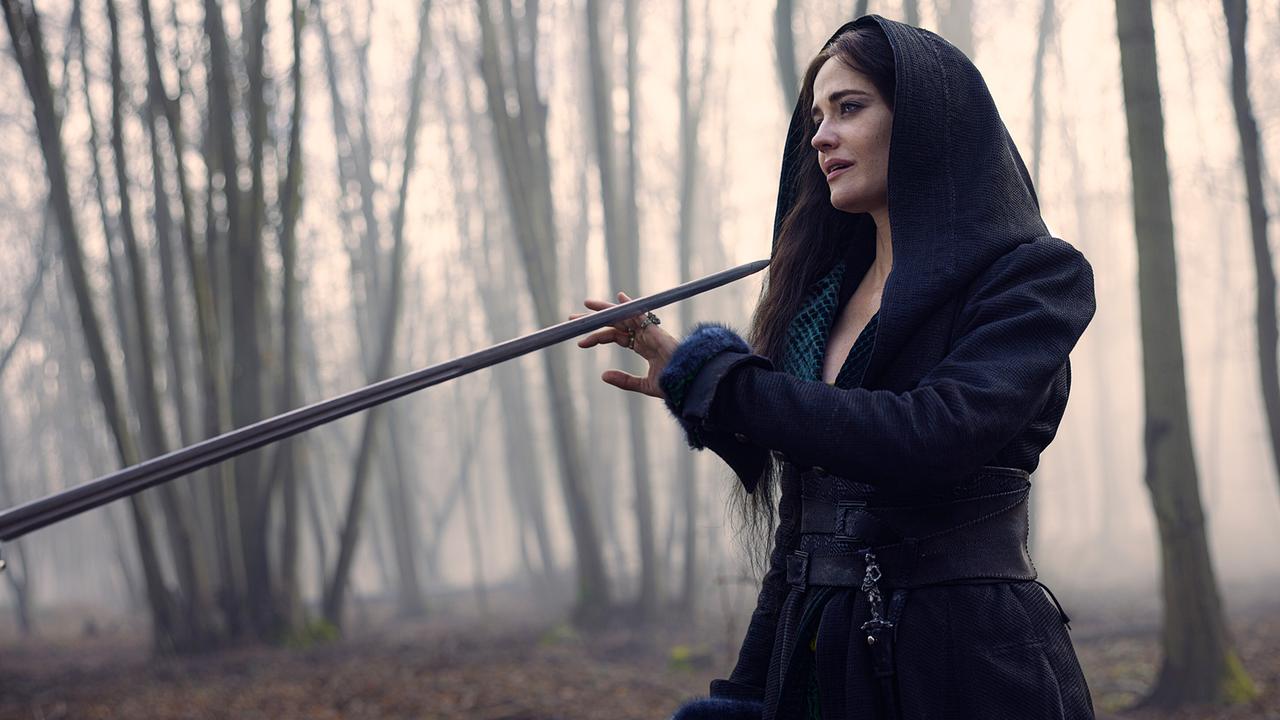 © ORF/Constantin Film/Ben King Eine Frau in dunklem Kapuzenmantel steht in einem nebligen Wald, mit der rechten Hand schiebt sie einen auf sich gerichteten Degen zur Seite