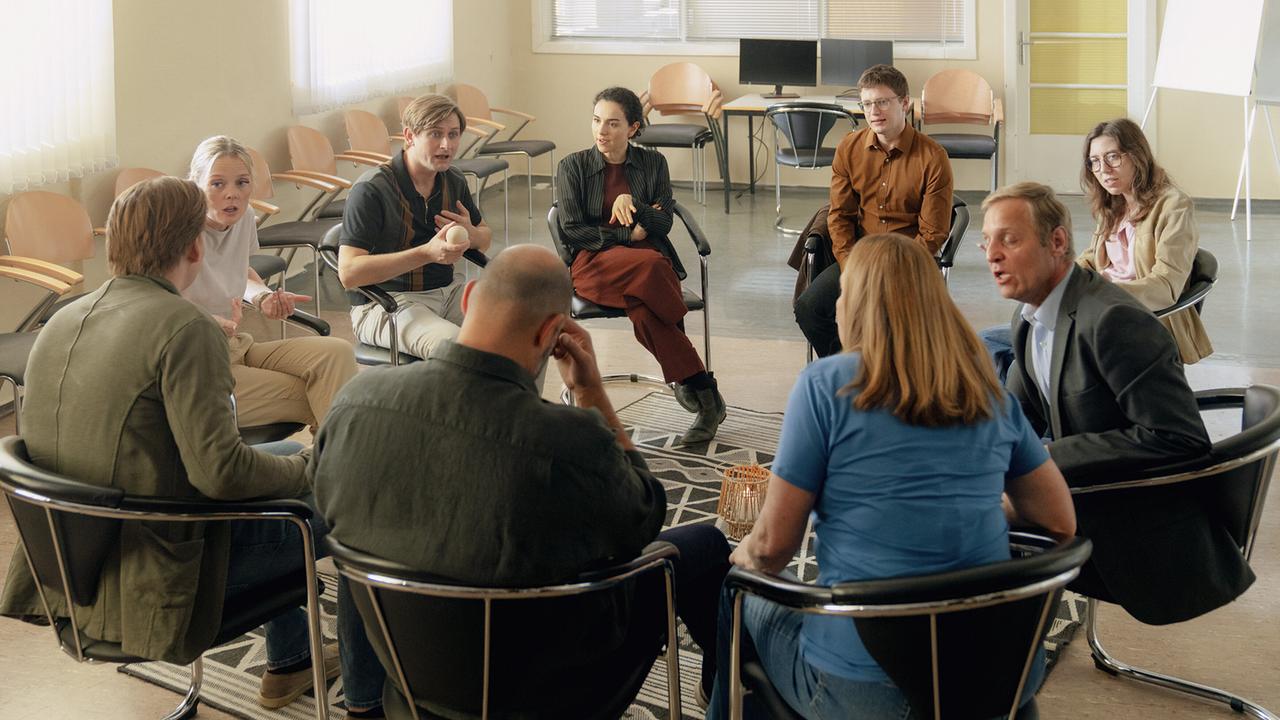 Neun Personen sitzen in einem Stuhlkreis und unterhalten sich im Rahmen eines Seminars.