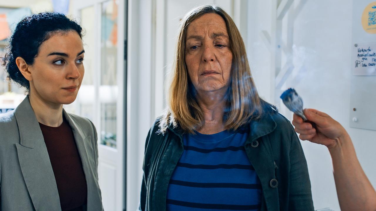 Heidi und Gerti stehen untertags nebeneinander in einem hellen Innenraum und schauen ernst.