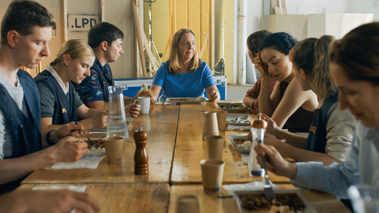 © ORF/Lotus Film Mehrere Menschen sitzen an einem langen Holztisch mit Gerti am Tischende und essen gemeinsam.