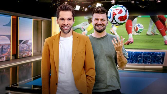 Die Präsentatoren Philipp Maschl und Thomas Seidl, der einen Fußball in die Luft wirft, stehen im Studio der "Fußball Show", hinter ihnen läuft eine Fußballszene.