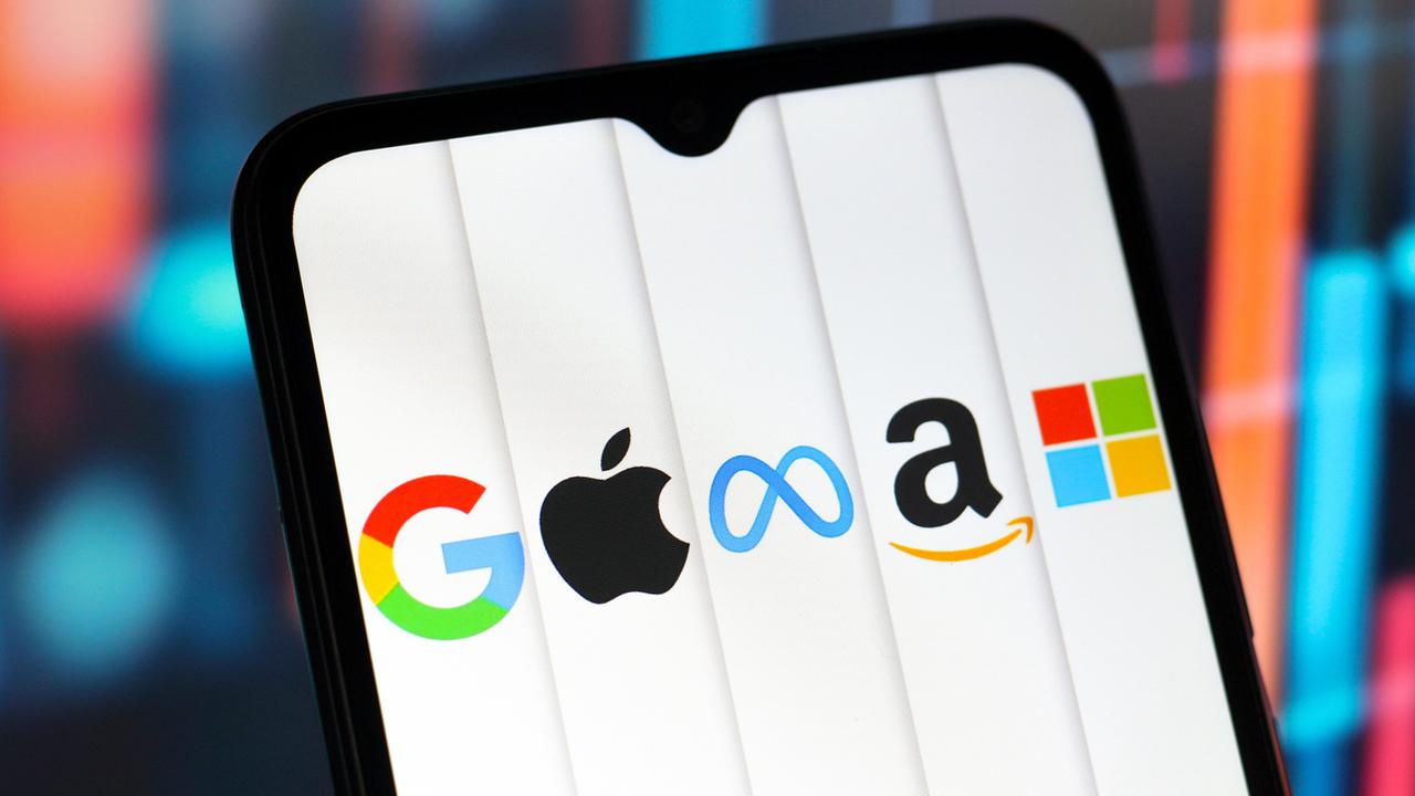 Auf dem Display eines Handys sind die Logos von Google, Apple, Meta, Amazon und Microsoft zu sehen