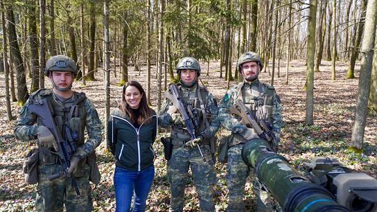 Lisa Gadenstätter steht mit einer Gruppe von Grundwehrdienern während einer Gefechtsübung in einem Wald.