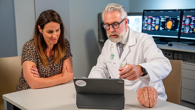 © ORF/Neulandfilm/Stefan Vucsina Neurologe Christian Enzinger erklärt Lisa Gadenstätter anhand eines Tablets und eines Gehirnmodells neurologische Aufnahmen.