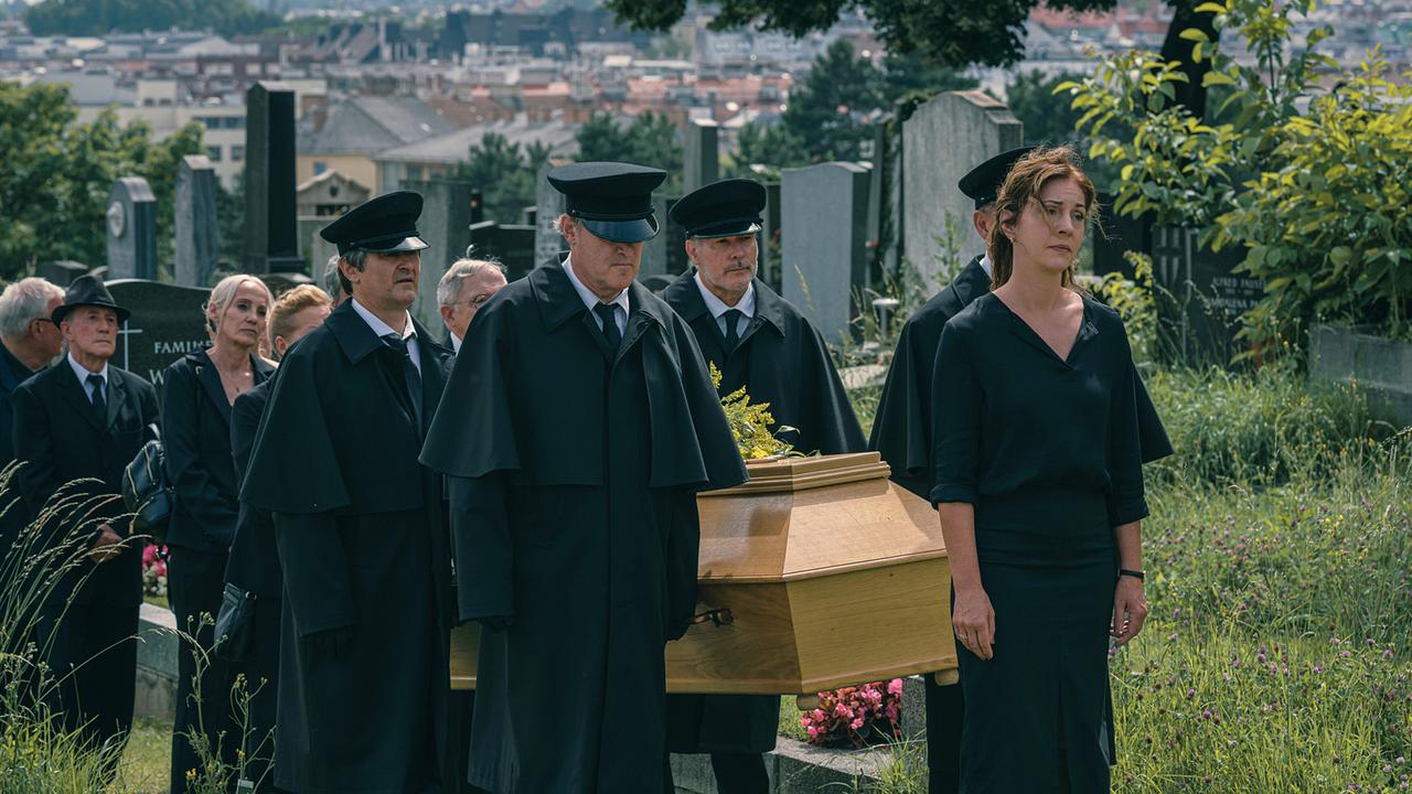 © ORF/Amazon/MGM Ein Trauerzug geht mit einem Sarg über den Friedhof, eine schwarz gekleidete Frau geht voran